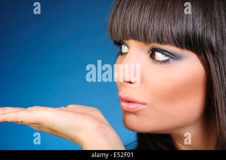 Schöne Brünette junge Frau Holding Palm in der Nähe von ihrem Gesicht, Studio gedreht Stockfoto
