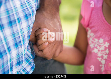 Ein kleines Kind in einem rosa Kleid ihres Vaters Hand hält. Stockfoto
