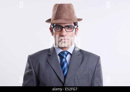 Porträt von zuversichtlich Geschäftsmann mit Hut und Brille vor grauem Hintergrund Stockfoto
