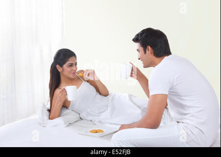 Glückliches Liebespaar im Bett frühstücken Stockfoto
