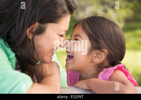 Eine Mutter im Park mit ihrer Tochter, lachen und küssen einander.