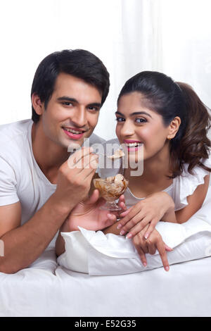 Porträt des jungen Paares Schokoladeneis im Bett genießen Stockfoto