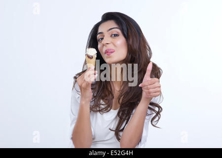 Verspielte junge Frau necken gedrückter Eistüte auf weißem Hintergrund Stockfoto