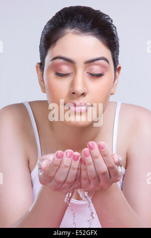 Schöne Frau waschen Gesicht vor grauem Hintergrund Stockfoto