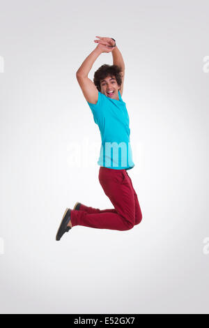 Voller Länge Seitenansicht begeistert jungen Mannes springen über weißem Hintergrund Stockfoto