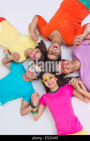 Direkt über dem Schuss der happy Friends Hand in Hand beim liegen im Kreis auf weißem Hintergrund Stockfoto