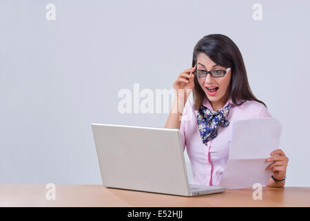 Überrascht junge Geschäftsfrau mit Laptop am Schreibtisch Stockfoto