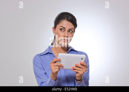 Nachdenklich Geschäftsfrau hält digitale Tablet über grauen Hintergrund Stockfoto