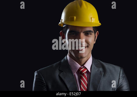 Porträt von lächelnden Geschäftsmann tragen Bauarbeiterhelm auf schwarzem Hintergrund Stockfoto