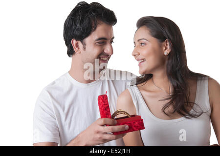 Liebevoller junger Mann gifting Armreifen an Frau auf weißem Hintergrund Stockfoto