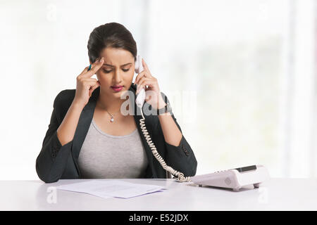 Gespannten Geschäftsfrau Beantwortung Telefon am Schreibtisch Stockfoto