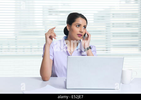 Geschäftsfrau Beantwortung Handy am Schreibtisch Stockfoto