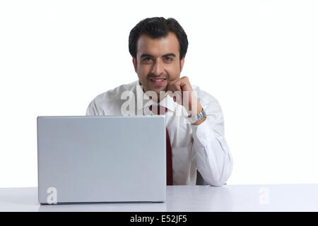 Porträt von lächelnden Geschäftsmann mit Laptop am Schreibtisch vor weißem Hintergrund Stockfoto