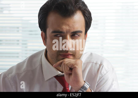 Nachdenklich Geschäftsmann mit Hand am Kinn im Büro Stockfoto