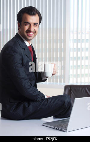 Seite Ansicht Bildniss glücklich Geschäftsmann Kaffeetrinken am Schreibtisch Stockfoto