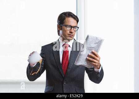 Geschäftsmann verschüttet Kaffee beim lesen Zeitung im Büro Stockfoto