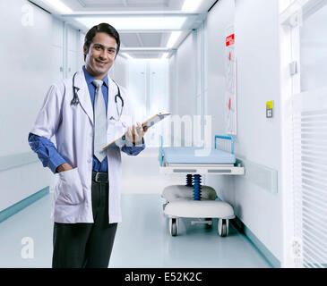Porträt von zuversichtlich männlichen Arzt hält Zwischenablage im Krankenhausflur Stockfoto