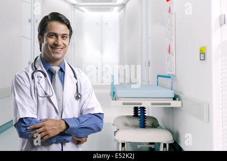 Porträt des Lächelns männlichen Arzt stehend Arme gekreuzt im Krankenhausflur Stockfoto