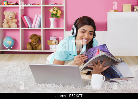 Junge Frau Musikhören während des Lesens Magazin zu Hause Stockfoto