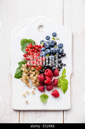 Mischung aus frischen Beeren mit Blättern auf rustikalen hölzernen Hintergrund Stockfoto