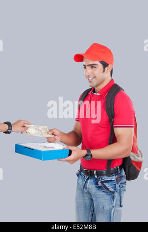 Lächelnd Pizzamann erhalten Geld von Kunden vor grauem Hintergrund Stockfoto