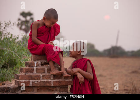 Zwei junge Mönche genießen Sie einen ruhigen Moment am Ende des Tages beim Sonnenuntergang auf der Ebene von Bagan in Myanmar. Stockfoto