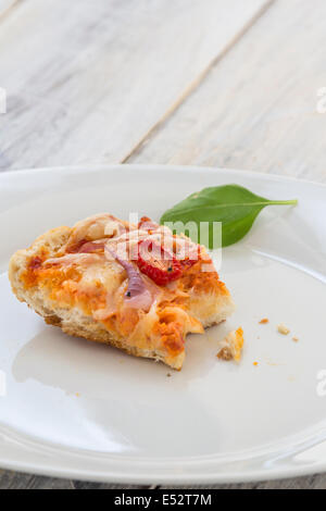 übrig gebliebene Pizza vom Vortag auf einer Platte auf einem rustikalen Holztisch Stockfoto