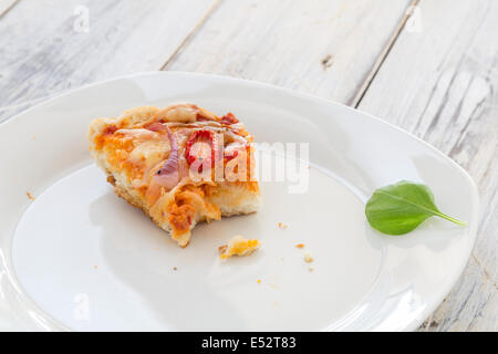 übrig gebliebene Pizza vom Vortag auf einer Platte auf einem rustikalen Holztisch Stockfoto