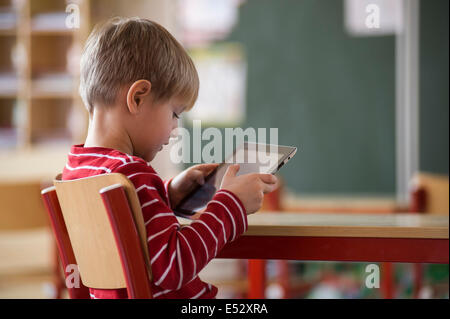 Schuljunge im Klassenzimmer mit iPad Stockfoto