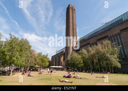 London, UK. 18. Juli 2014. Wetter: Die Hauptstadt erfährt den heißesten Tag des Jahres soweit Temperaturen bis 30 C stieg. Büroangestellte und Touristen gleichermaßen genossen die Wärme und Sonne nach dem Gewitter der vergangenen Nacht.  Im Bild: Menschen nehmen Sie ein Sonnenbad vor dem Tate Modern Museum. Bildnachweis: Stephen Chung/Alamy Live-Nachrichten Stockfoto