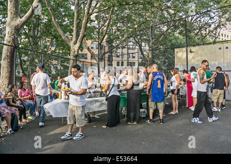 hungernden Menschen in Linie zum Picknick Abendessen servieren, als Mann Tisch mit Platte verlässt gestapelt hoch mit Mais & Backhendl Stockfoto
