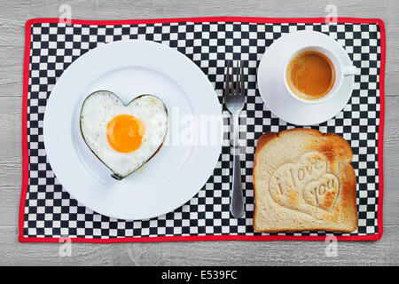 Spiegelei in Herzform und Toast mit Liebesbotschaft. Frühstück für einen lieben Menschen Stockfoto