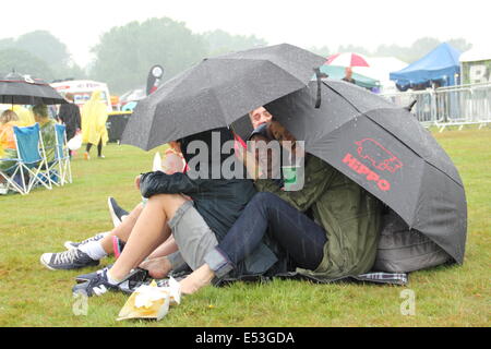 Nottingham East Midlands, UK.  19. Juli 2014. Festivalbesucher nehmen Sie Abdeckung unter Sonnenschirmen, wie ein Platzregen Glanz-Musikfestival in Wollaton Hall in Nottingham trifft. Bildnachweis: Deborah Vernon/Alamy Live-Nachrichten Stockfoto