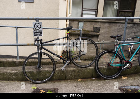 Fahrräder auf Geländer neben einer Ankündigung Fahrräder gesperrt werden entfernt, es in Trinity College Dublin, Irland Stockfoto