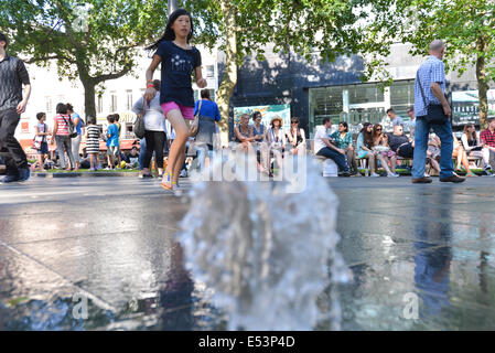 Leicester Square, London, UK. 19. Juli 2014. Londoner und Touristen genießen die Brunnen am Leicester Square rund um die Statue von William Shakespeare. Bildnachweis: Matthew Chattle/Alamy Live-Nachrichten Stockfoto