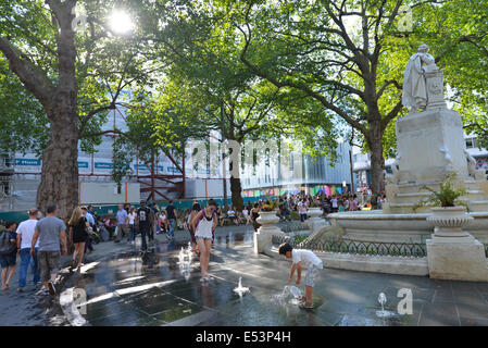 Leicester Square, London, UK. 19. Juli 2014. Londoner und Touristen genießen die Brunnen am Leicester Square rund um die Statue von William Shakespeare. Bildnachweis: Matthew Chattle/Alamy Live-Nachrichten Stockfoto