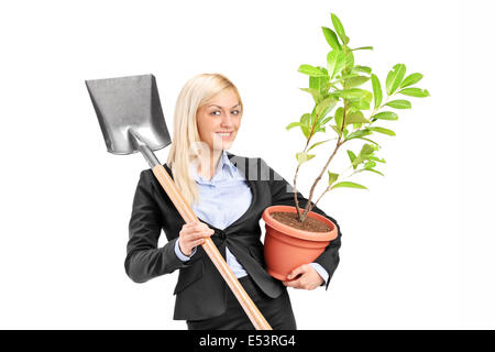 Junge Frau hält eine Schaufel und eine Pflanze, die auf weißen Hintergrund isoliert Stockfoto