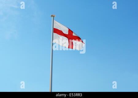Die englische Nationalflagge, Str. Georges Kreuz, fliegen aus einer Fahnenstange gegen ein strahlend blauer Himmel Stockfoto