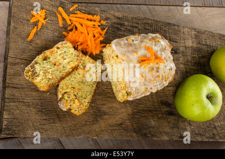 Karotte Apfelkuchen auf Holztisch mit geriebenen Karotten Stockfoto