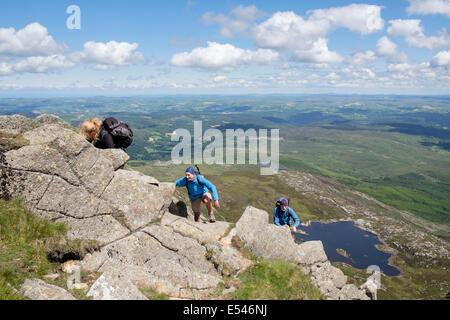 Drei Wanderer kriechen bis Felsen auf Carnedd Moel Siabod Daear Ddu East Ridge mit Blick hinunter zum Llyn y-Foel Snowdonia National Park (Eryri) Wales UK Stockfoto