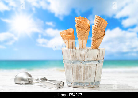 Stapel von leeren Eiscreme Waffel Kegel mit Schaufel und Strand Weichzeichnen Hintergrund Stockfoto