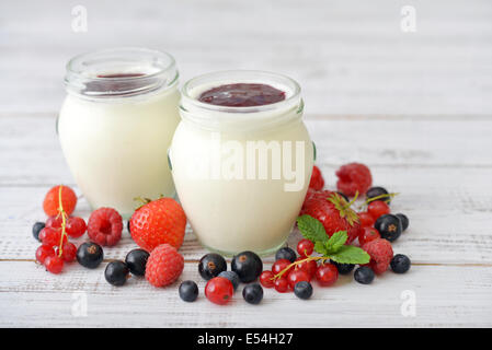 Joghurt mit reif frischen Beeren in Gläser auf hölzernen Hintergrund Stockfoto