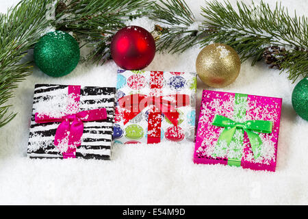 Draufsicht der verpackte Geschenke mit Schnee und immergrünen Zweigen sowie Tannenzapfen und Weihnachtsschmuck Stockfoto