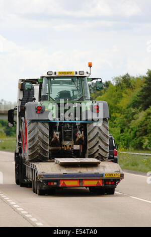 Ein Tieflader schleppen einen Traktor auf der A28 einspurigen Straße in der Nähe von Ashford in Kent, England Stockfoto