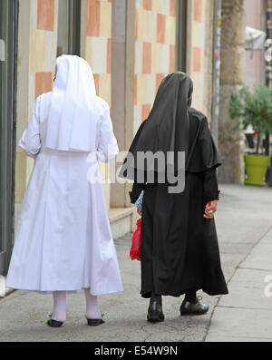 zwei alte Schwestern mit schwarzen Anzug und weißes Kleid zu Fuß in der Stadt Stockfoto