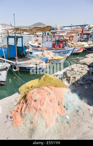 Bunte Fischerboote und Netze am Kai im Hafen von Kusadasi, Türkei Ägäis an einem sonnigen Sommertag mit blauem Himmel aufgetürmt Stockfoto