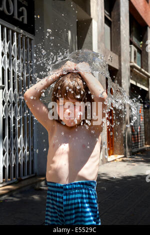 5 Jahre alter Junge mit Wasser gefüllten Ballons über seinem Kopf explodiert. Stockfoto
