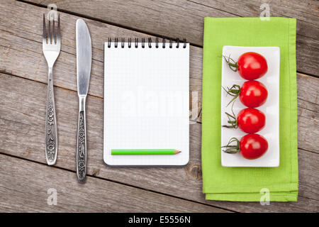 Frische Tomaten, Tafelsilber und Notizblock für textfreiraum auf Holztisch Hintergrund Stockfoto