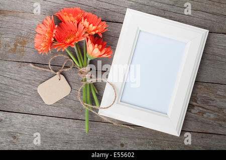 Blumenstrauß Gerbera und Fotorahmen auf Holztisch Stockfoto