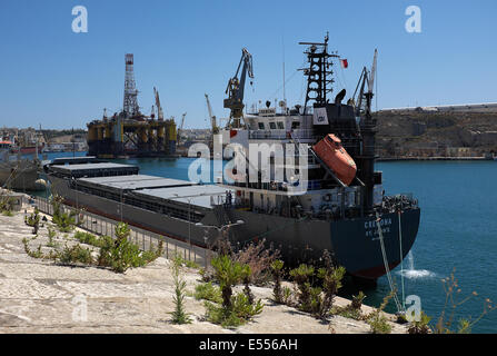 Frachtschiff Cremona vertäut aus Senglea, Valletta Malta mit der Transocean Amirante Bohrinsel im Hintergrund Stockfoto